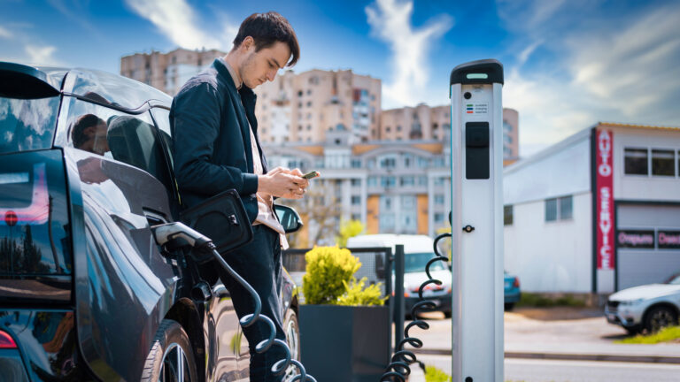 man charging his electric car charge station using smartphone TheHomeQuality